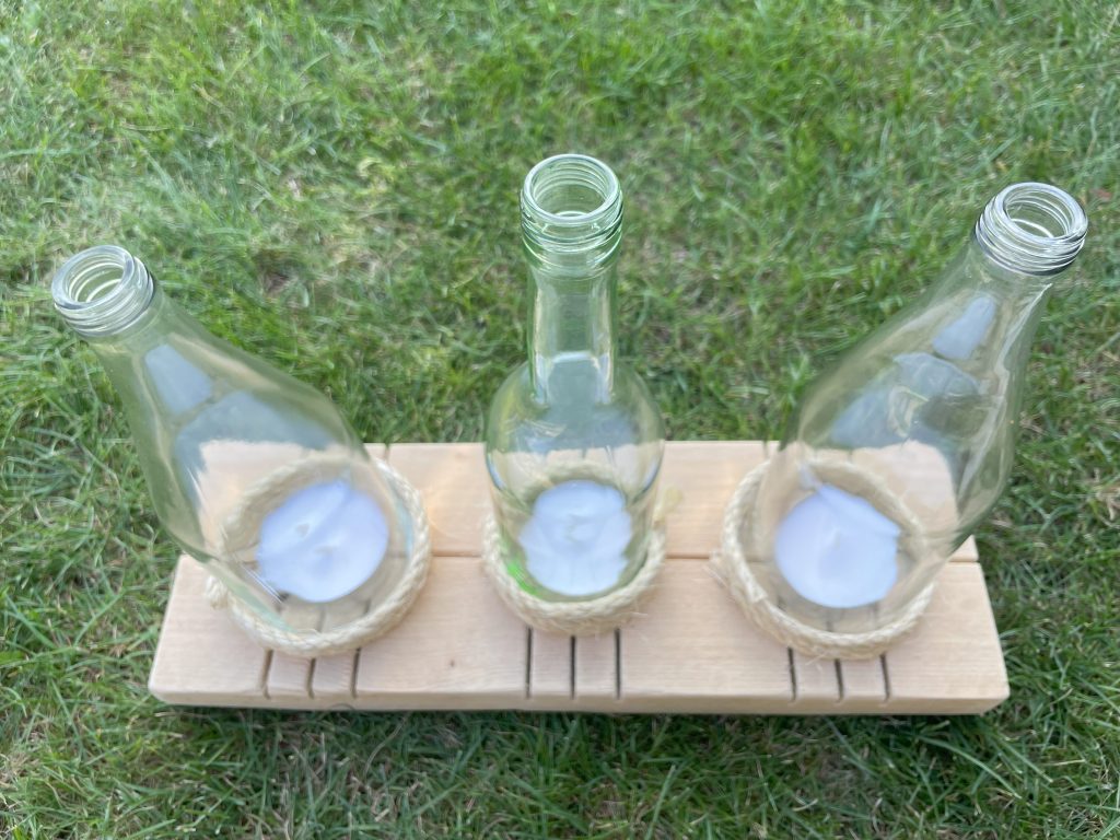 Rustikale Kerzenhalter aus Holz und Weinflaschen.